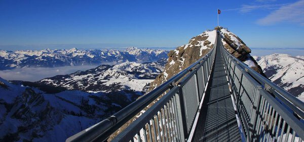 Suspension bridge connecting two peaks. Travel destination in Sw