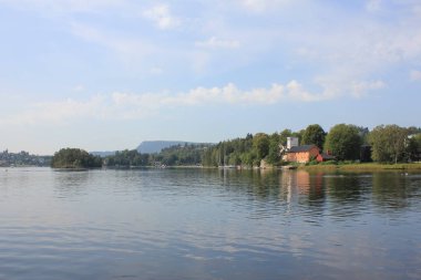 Norveç, Oslo yakınlarındaki fiyordun kıyısındaki yeşil orman ve eski fabrika.