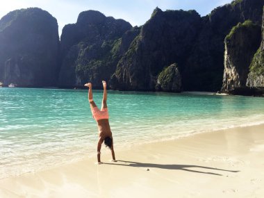 Bir kumsalda gösteren başparmak genç adam