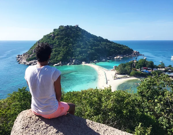 Hombre sentado en una roca cerca de una playa y mirando al cielo — Foto de Stock