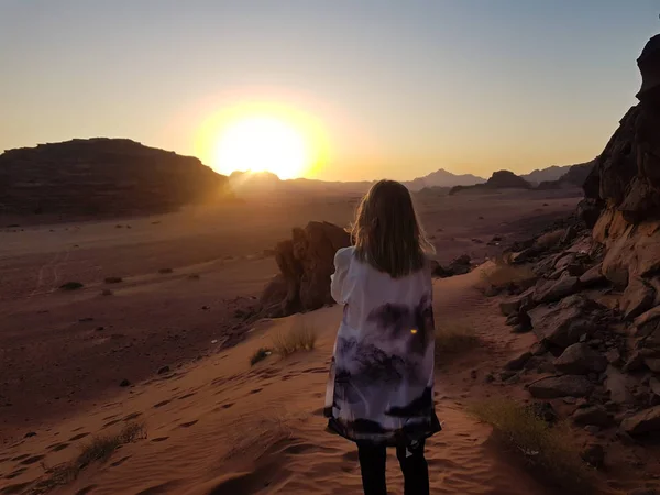 Sırtında duran bir kız. Wadi Rum çölünde gün batımını izliyorum, Jordan. Çölde gün batımında turuncu kumla. Hayatın geri kalanı için romantik atmosfer ve anılar..