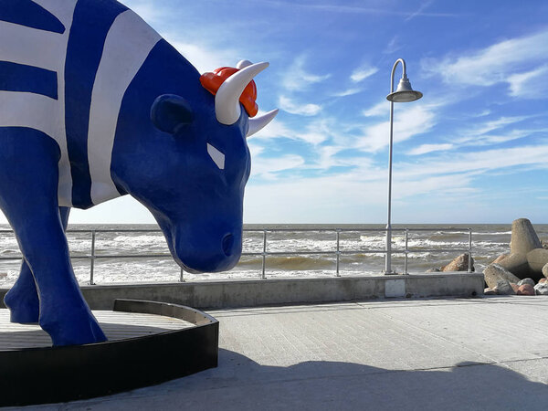 Cow in a stripy t-shirt is a symbol for latvian sailors. Ventspils is the city of seamen. Bull with horns that stands against the Baltic sea.