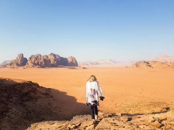 Girl take a walk at Wadi Rum desert, Jordan. Girl\'s back and picturesque view at the desert. Surface of Mars on Earth.