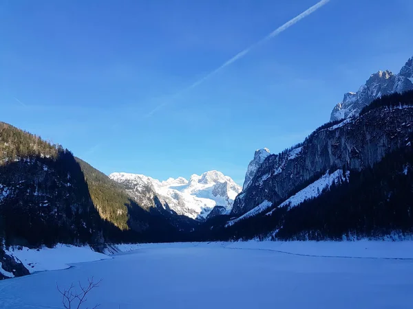 Beautiful view at the snowy mountains and frozen lake at the Gosausee, Austria. Snowy alpine peaks in shadows.