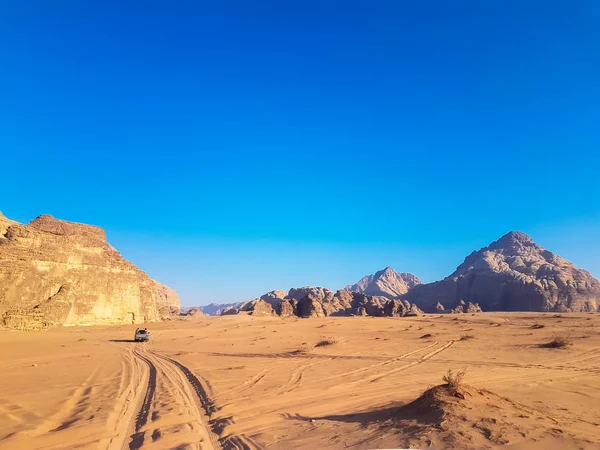 Wadi Rum çölünde günbatımı safarisi, Jordan. Yataklı kamyonet turu. Ünlü çölde, iki kayalık dağın ortasında, kum üzerinde araba sürüyor.. 