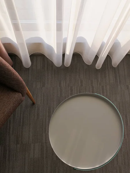 Round end table mock up in a hotel interior. Empty metal coffee table and chair on a carpet top view. Sun rays that shine through a curtained window in a hotel room.