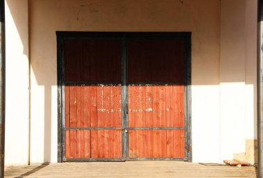 Kilitli olan kırmızı ahır kapısı. Bina cephesini süsleyen ahşap bir depo kapısı. Kapalı bir ahır kapısının önü.. 
