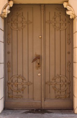 Metal parçalı ahşap çift kapı. Küçük melek heykelleri ve dekoratif kapı kolu gibi ilginç elementlerle dolu güzel bir sokak kapısı..  
