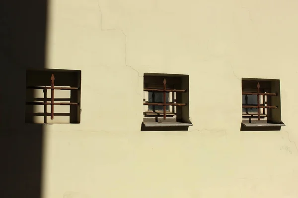 Alçı duvardan yapılmış üç küçük pencere. Bina cephesinde simetri. 
