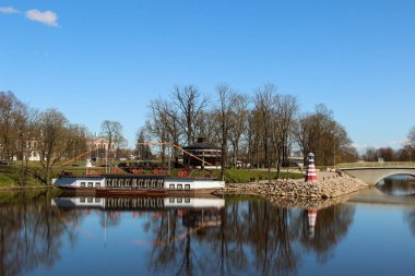Sahilde deniz feneri ve nehir teknesi olan şehir kanalı. Jelgava şehrindeki popüler su manzarası. 