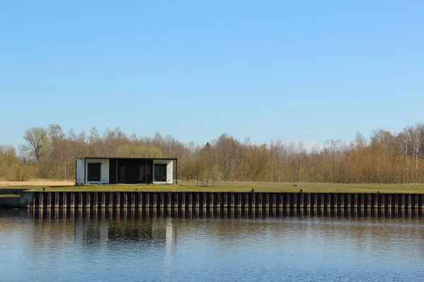 One-storey modular house that stand at the river shore. Container housing that stand aside from living area.