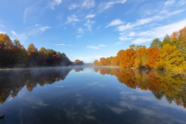 Туман на воде и осенние цветные деревья — стоковое фото
