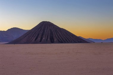 Günbatımında siyah dağ ve sarı gökyüzü