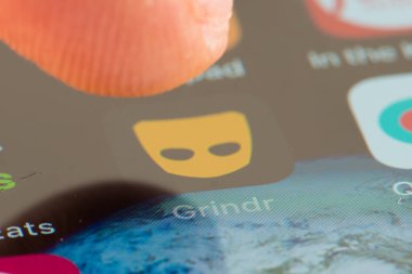 MINNEAPOLIS, MINNESOTA / USA - 25 Nisan 2019: Grindr uygulamasına / uygulamasına erişmek için Apple i-phone kullanan kişi