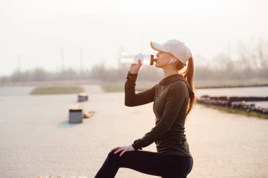 Güzel bir kız sabah antrenmanında şişeden su içiyor.