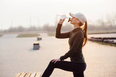 Güzel bir kız sabah antrenmanında şişeden su içiyor.