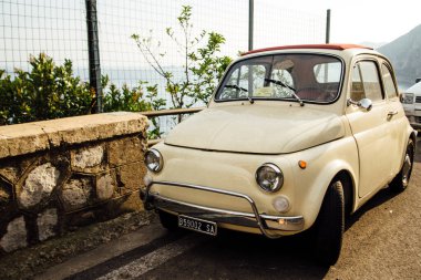 Küçük bir retro güzel bej araba fiat 500 deniz kenarında bir halka üzerinde duruyor