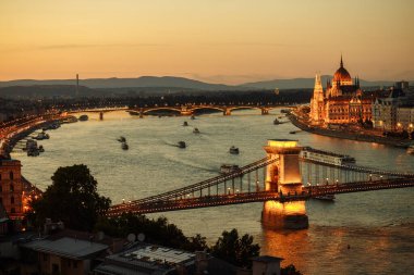 Tuna Nehri 'ndeki Budapeşte şehrinin gece manzarası. Üzerinde açık köprü ve parlamento bulunan gemiler yelken açıyor.