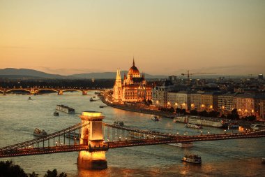 Tuna Nehri 'ndeki Budapeşte şehrinin gece manzarası. Üzerinde açık köprü ve parlamento bulunan gemiler yelken açıyor.