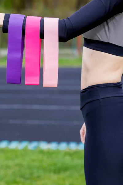 Fitness kızı elinde üç tane sakız tutuyor. Güçlü, orta boy, spor için hafif.
