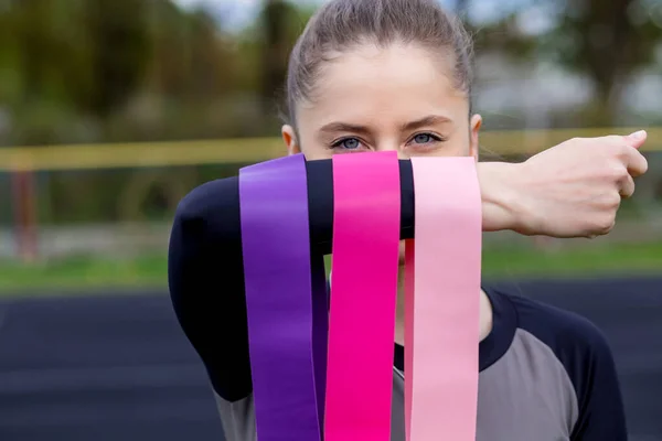 Fitness kızı elinde üç tane sakız tutuyor. Güçlü, orta boy, spor için hafif.