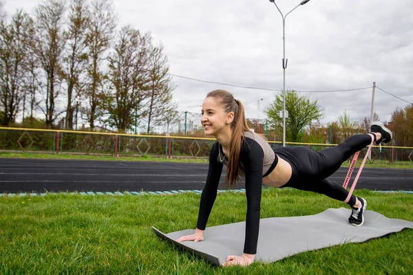 fitness girl on a plank position using fitness gum