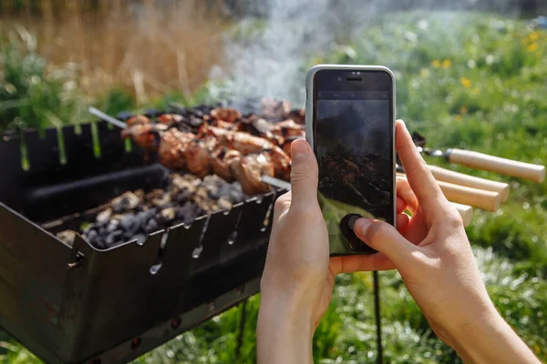 Kız akıllı telefondan barbekü kebabı fotoğrafı çekiyor.