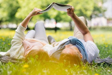 Bir çift kitap okurken parkta dinleniyor..