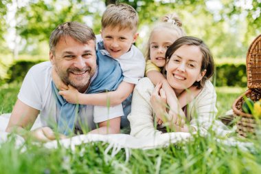 Anne ve baba çimenlerin üzerinde uzanmış çocuklarını tutuyorlar..