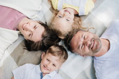 Aile battaniyeye uzanmış kameraya bakıyor..