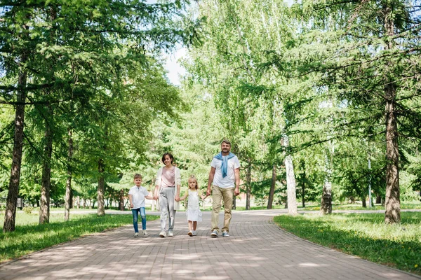 Duża szczęśliwa rodzina z dwójką dzieci spaceruje po parku strzał z daleka. — Zdjęcie stockowe