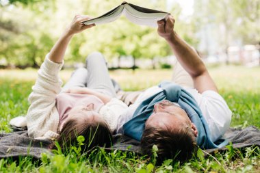 Bir çift kitap okurken parkta dinleniyor..