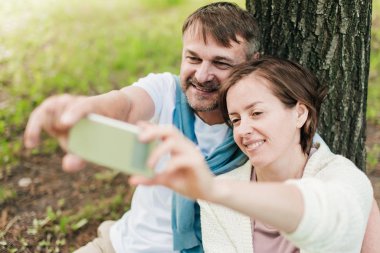 Parkta çimlerin üzerinde selfie çeken çift..