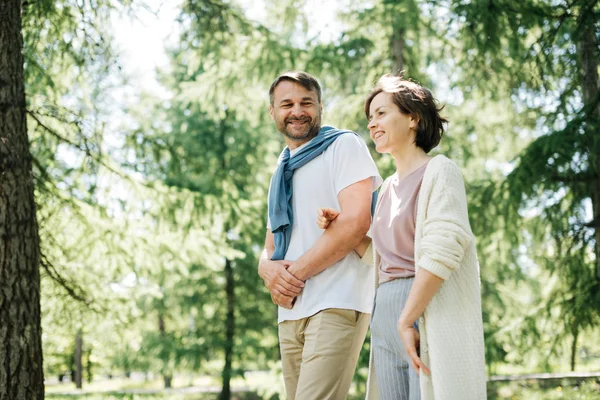 Paar mittleren Alters geht Händchen haltend durch den Park. — Stockfoto