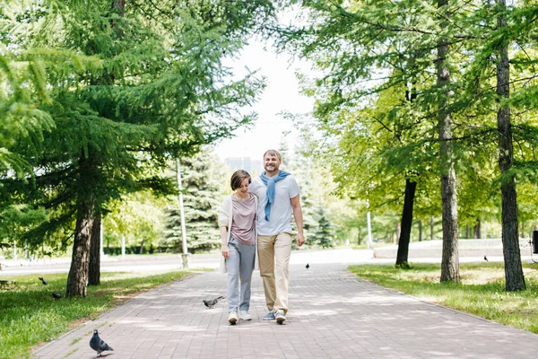 Ehepaar mittleren Alters spaziert am Wochenende gemeinsam durch den Park. — Stockfoto