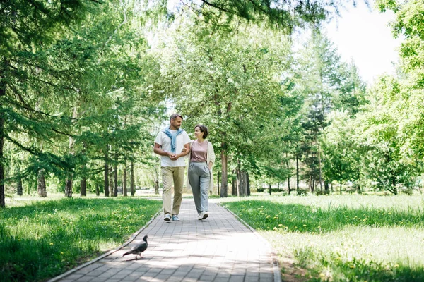 Ehepaar mittleren Alters spaziert am Wochenende gemeinsam durch den Park. — Stockfoto