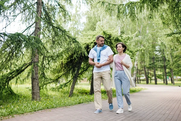 Couple walking in the park among the trees.