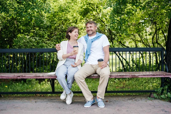 Middle-aged married couple drink coffee on the bench. — Stock Photo, Image