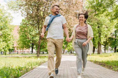 Orta yaşlı evli çift parkta koşuyor..