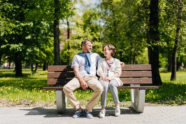 Middle-aged married couple resting in the park shot from distance. — Stock Photo, Image