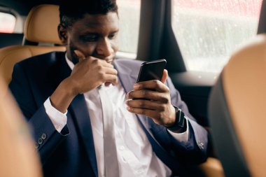 İş adamı arabada otururken telefonla konuşuyor..