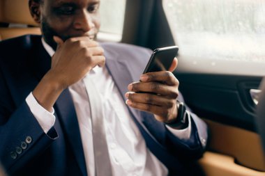 Arka koltuktaki adam telefon ekranına bakıyor..