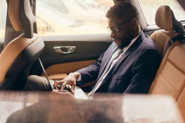 Arka koltukta laptopla çalışan bir adam var..