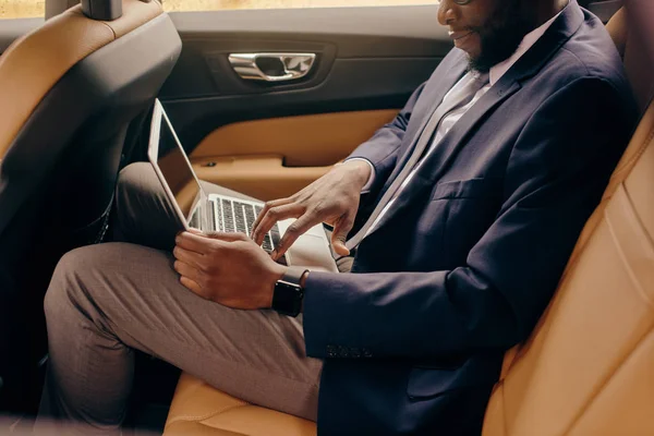 Közelkép egy férfiról, aki a kocsiban ül és a laptopon dolgozik.. — Stock Fotó