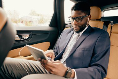 Adam araba sürerken tablet ekranda kayıyor.