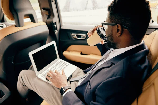 Uomo che beve caffè mentre lavora al computer portatile . — Foto Stock