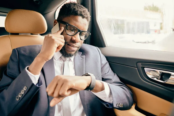 Businessman in car checks time on his watch.