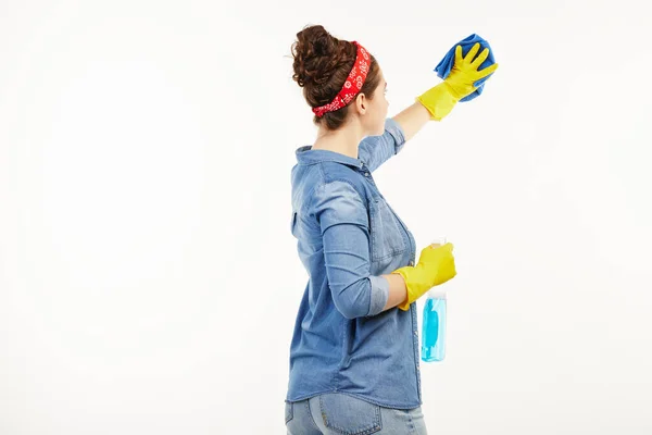 Όμορφη γυναίκα με ρούχα εργασίας χρησιμοποιεί υλικά καθαρισμού παραθύρων που δεν αντιμετωπίζουν την κάμερα. — Φωτογραφία Αρχείου
