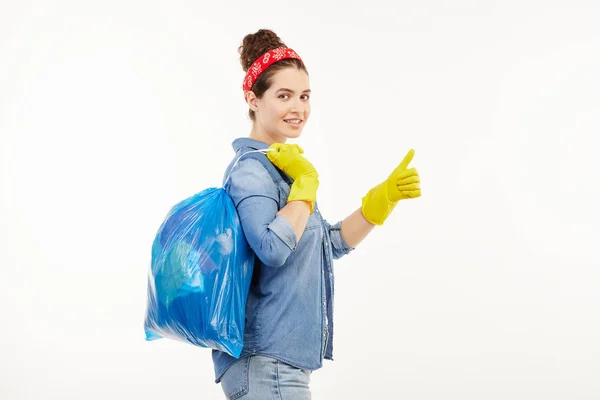 穿着工作服的漂亮女人拿着一个蓝色的垃圾袋. — 图库照片