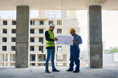 İki mühendis her ikisi de tutun Taslaklar tartışmak.